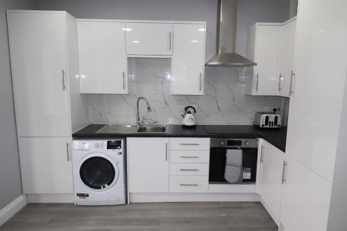 a white kitchen with a sink and a dishwasher at NEW 1 BED FLAT IN DARTFORD- 40 Mins into London -SLEEPS 3-FIBRE BROADBAND-PARKING-10 MINS WALK TO CITY CENTRE in Kent