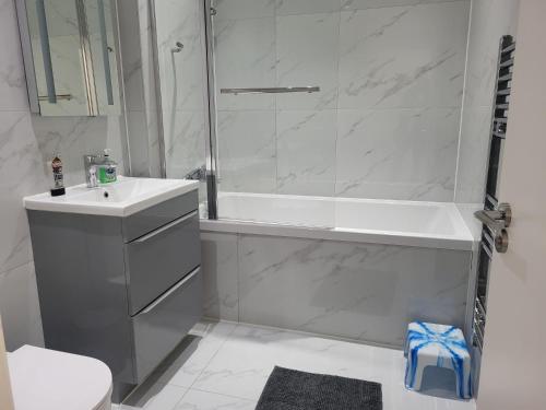 a white bathroom with a tub and a sink at NEW 1 BED FLAT IN DARTFORD- 40 Mins into London -SLEEPS 3-FIBRE BROADBAND-PARKING-10 MINS WALK TO CITY CENTRE in Kent