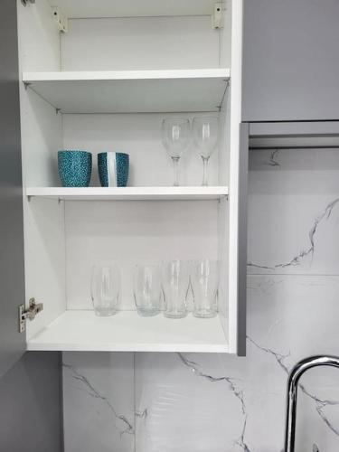 a white cabinet with wine glasses in it at NEW 1 BED FLAT IN DARTFORD- 40 Mins into London -SLEEPS 3-FIBRE BROADBAND-PARKING-10 MINS WALK TO CITY CENTRE in Kent