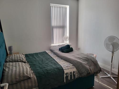 a bedroom with a bed with a fan and a window at NEW 1 BED FLAT IN DARTFORD- 40 Mins into London -SLEEPS 3-FIBRE BROADBAND-PARKING-10 MINS WALK TO CITY CENTRE in Kent