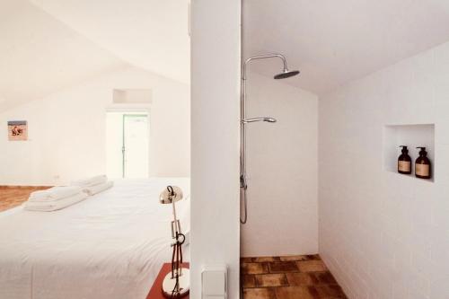 a white bedroom with a shower and a bed at Casa Dona Antonia in São Bartolomeu de Messines