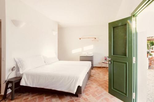 a bedroom with a white bed and a green door at Casa Dona Antonia in São Bartolomeu de Messines