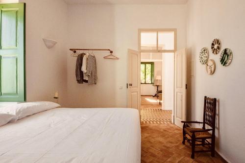 a bedroom with a white bed and a chair at Casa Dona Antonia in São Bartolomeu de Messines
