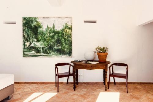 a table and two chairs in a room with a painting at Casa Dona Antonia in São Bartolomeu de Messines