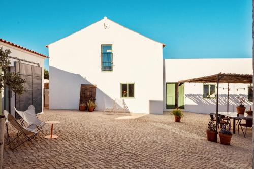 a large white building with a table and chairs at Casa Dona Antonia in São Bartolomeu de Messines