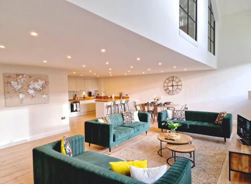 a living room with green couches and a kitchen at The Academy House by Bevolve in Shrewsbury