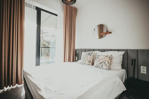 ein Bett mit weißer Bettwäsche und Kissen in einem Schlafzimmer in der Unterkunft 2Homerent Shellter 117 in Rogowo