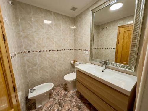 ein Badezimmer mit einem Waschbecken, einem WC und einem Spiegel in der Unterkunft Modern Apartment On Playa Del Cura in Torrevieja