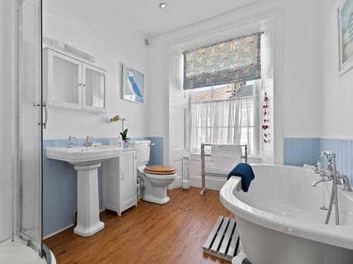 a bathroom with a tub and a sink and a toilet at New Cross House in St. Davids