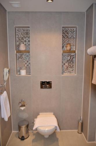 a bathroom with a toilet and three shelves on the wall at True Beach Resort in Marsa Alam City