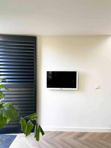 a room with a tv on a white wall at Lovely private cottage near Amsterdam in Broek in Waterland