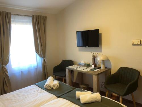 a hotel room with a bed and a desk with two chairs at Kenguru Panzió és Csárda in Hódmezővásárhely