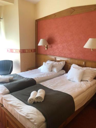 two beds in a hotel room with towels on them at Kenguru Panzió és Csárda in Hódmezővásárhely