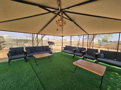 un gruppo di divani e tavoli sotto ombrello di استراحة دار العين a Al Ain