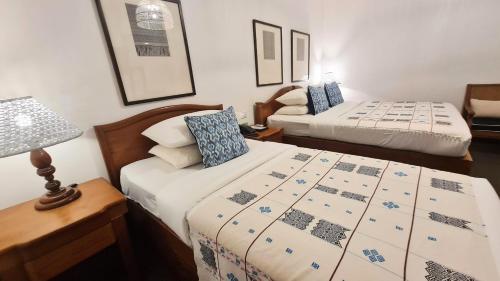 a bedroom with two beds and a lamp and a table at Winner Inn in Yangon
