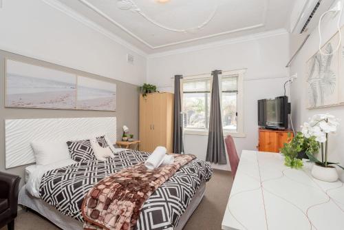 a bedroom with a bed and a table and a television at Private Ensuite Queen room near Sydney Airport in Sydney