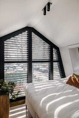 a bedroom with a white bed and a large window at Lovely private cottage near Amsterdam in Broek in Waterland