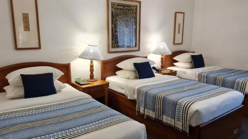 a hotel room with two beds and two lamps at Winner Inn in Yangon