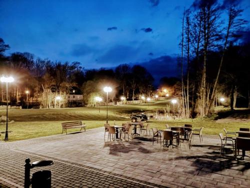 a patio with tables and chairs in a park at night at Dworek Hołny in Hołny Mejera
