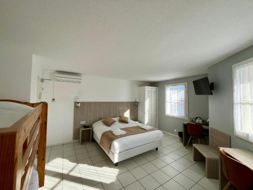 - une chambre avec un lit, un bureau et une télévision dans l'établissement Hôtel Les Arcades, à Saintes-Maries-de-la-Mer
