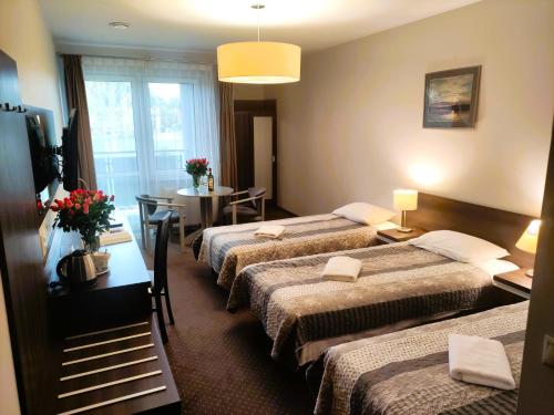 um quarto de hotel com três camas e uma mesa em Pensjonat u Marianny em Augustów