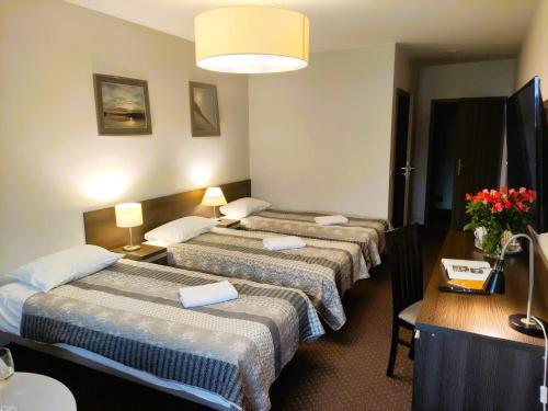 um quarto de hotel com três camas e uma mesa com flores em Pensjonat u Marianny em Augustów
