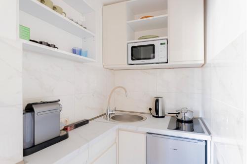 a small kitchen with a sink and a microwave at Újbuda Rest Apartment With Air Condition and Balcony in Budapest