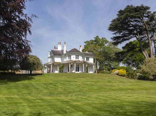 a large white house on a lush green field at Denham Mount in Buckinghamshire