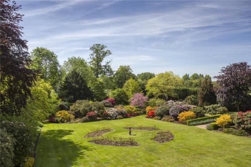 a garden with a large lawn with flowers and trees at Denham Mount in Buckinghamshire