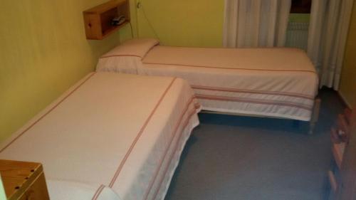 two twin beds in a small room with at Albergo Trieste in Tambre dʼAlpago