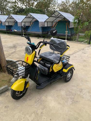 a yellow scooter parked in front of some tents at Baan Suan Madam บ้านสวนมาดามวังน้ำเขียว in Ban Khlong Ta Sang