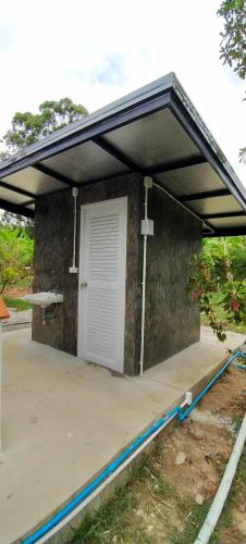 a building with a garage with a white door at Baan Suan Madam บ้านสวนมาดามวังน้ำเขียว in Ban Khlong Ta Sang