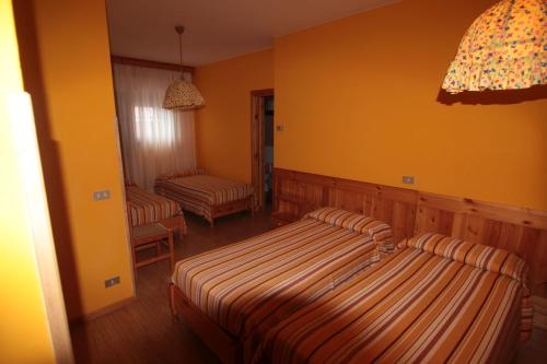 two beds in a room with yellow walls at Albergo Trieste in Tambre dʼAlpago