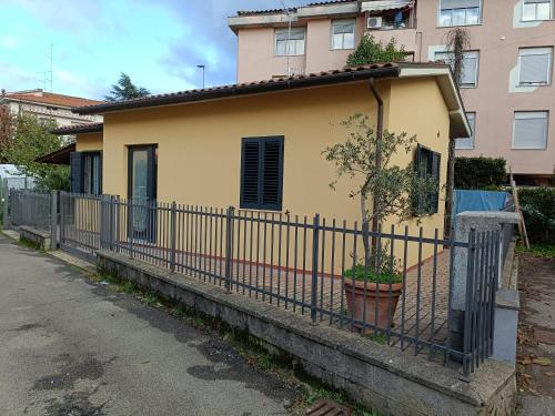 a yellow house with a fence and a tree at A Casa di Amici in Arezzo