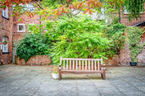 a wooden bench sitting in front of a tree at Gamul Place - Quiet City Centre in Chester