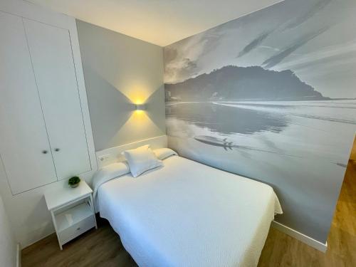 a bedroom with a picture of the ocean on the wall at Pensión Txiki Polit in Zarautz