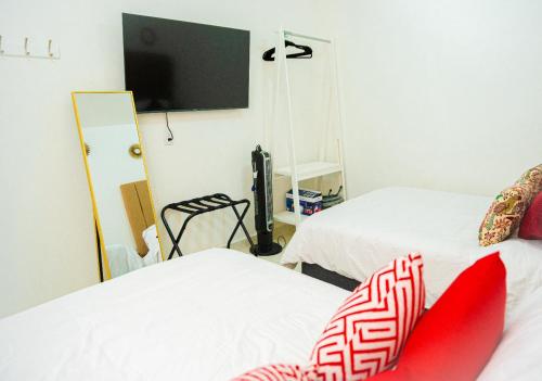 a room with two beds and a tv on the wall at Hotel Bungalows Casa Blanca in Tenancingo de Degollado