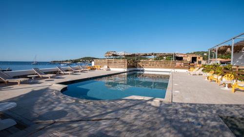 una piscina con sillas y el océano en el fondo en Valinco Village, en Porto Pollo