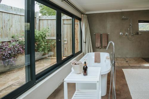 a bathroom with a tub and a sink and windows at Rockdell Lodge in Stutterheim