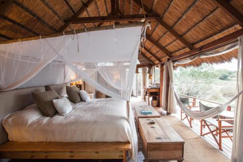 a bedroom with a bed and a wooden table at Sindabezi Island Camp in Simonga