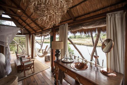 a room with a table with a mirror and a window at Sindabezi Island Camp in Simonga