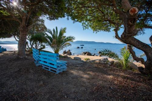un banco azul sentado en la playa cerca del agua en Valinco Village, en Porto Pollo
