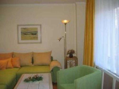 ein Wohnzimmer mit einem grünen Sofa und einem Tisch in der Unterkunft Haus am Hang Pension garni in Scharbeutz