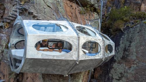a pod house on a cliff with two people inside at Starlodge Adventure Suites in Urubamba