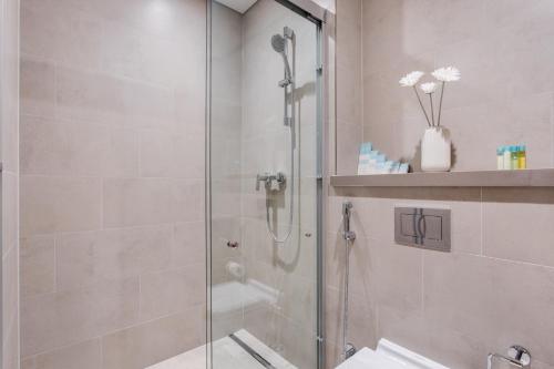 une douche avec une porte vitrée dans une salle de bain dans l'établissement STAY BY LATINEM Luxury 1BR Holiday Home W102 near Burj Khalifa, à Dubaï