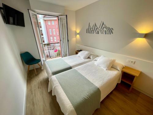 a hotel room with two beds and a window at Pensión Txiki Polit in Zarautz