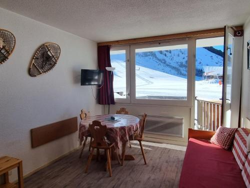 un salon avec une table et une grande fenêtre dans l'établissement Studio lumineux cabine ski-in/ski-out, 3/4 pers, vue pistes - FR-1-181-2595, à Aime La Plagne