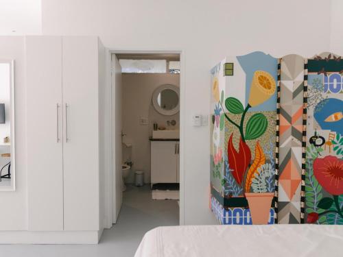 a bedroom with white walls and a colorful wall at McLeod's & Stuart's Cottage in Somerset West