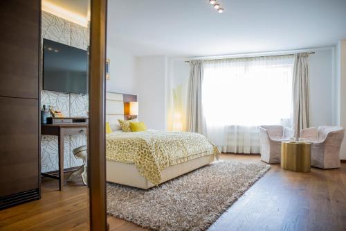 Schlafzimmer mit einem Bett, einem Schreibtisch und einem Fenster in der Unterkunft Iris Porsche Hotel & Restaurant in Mondsee