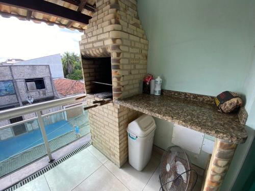 une cuisine avec une cheminée en brique à côté d'une piscine dans l'établissement The Férias | Suites Luxo, à Cabo Frio